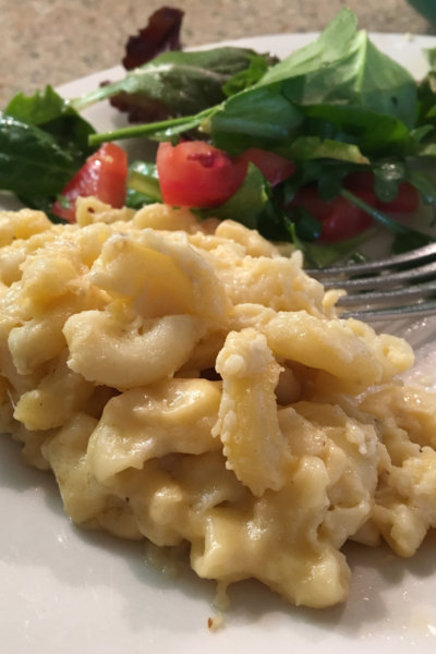 mac and cheese on white plate with salad